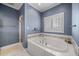 Bathroom featuring a large soaking tub, tiled walls, shower, and a window with shutters at 1005 Brookview Dr, Elon, NC 27244