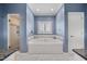 Bathroom featuring a soaking tub, tiled walls, a shower, and a window with shutters at 1005 Brookview Dr, Elon, NC 27244