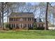 Beautiful two-story brick home with black shutters and a well-manicured lawn, surrounded by mature trees at 1005 Brookview Dr, Elon, NC 27244