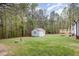 Large green backyard with a storage shed in the distance, adjacent to a wooded area at 120 Renee Dr, Wilson's Mills, NC 27577