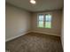 Bright, carpeted bedroom with a large window offering views of the green lawn and neighborhood at 141 Ruskin Dr, Smithfield, NC 27577