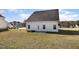 Home's exterior featuring a grassy yard, concrete patio, and white siding under a bright blue sky at 15 Woodworkers Way, Clayton, NC 27520