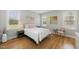 A cozy bedroom with warm hardwood floors, two windows, white bedding, and stylish decor at 184 Mort Harris Rd, Louisburg, NC 27549