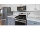Modern kitchen with stainless steel appliances, gray cabinets, white subway tile backsplash, and marble countertops at 184 Mort Harris Rd, Louisburg, NC 27549