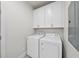 A bright, all-white laundry room featuring a new washer and dryer set and ample cabinet storage at 184 Mort Harris Rd, Louisburg, NC 27549