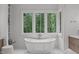 Bright bathroom with freestanding tub, marble floors, and forest view at 2200 Paddstowe Main Way, Wake Forest, NC 27587