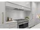 Kitchen with a stainless steel range and hood, stone backsplash, and modern white cabinetry at 2200 Paddstowe Main Way, Wake Forest, NC 27587