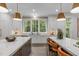 Bright kitchen showcasing double islands, stone countertops, pendant lights, and large windows overlooking nature at 2200 Paddstowe Main Way, Wake Forest, NC 27587