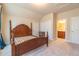 Bedroom features carpet, neutral paint, access to bathroom and closet, and a dark wood bed frame at 2620 Club Level Dr, Apex, NC 27523