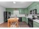 Bright kitchen featuring green cabinets, white countertops, black appliances, and wood breakfast island at 2808 Newquay St, Durham, NC 27705