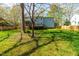 Spacious backyard with a large lawn, mature trees, a wooden deck, a screened porch, and a wood fence at 2868 Anfield Rd, Raleigh, NC 27606