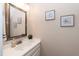 Well-lit powder room featuring a framed mirror, quartz counters and neutral color scheme at 2868 Anfield Rd, Raleigh, NC 27606