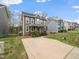 Exterior view of a two-story home with brown and gray siding, a driveway, and a green lawn at 329 Chamberlain Dr, Clayton, NC 27527