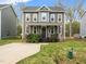 Two-story home featuring a well-maintained lawn, concrete driveway, and manicured shrubbery at 329 Chamberlain Dr, Clayton, NC 27527
