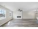 Expansive living room with wood-look floors, a cozy fireplace, large windows, and a stylish ceiling fan at 3717 Phillips W Way, Durham, NC 27713