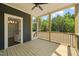 Covered back porch featuring wood flooring, a ceiling fan, and views of the wooded backyard at 390 Pilot Ridge Rd, Zebulon, NC 27597