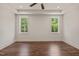 Serene bedroom featuring two windows offering pleasant views, a tray ceiling with a fan, and warm wood flooring at 390 Pilot Ridge Rd, Zebulon, NC 27597