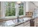 Bright kitchen with stainless steel sink and granite countertops; backyard view through large windows at 4121 Enfield Ridge Dr, Cary, NC 27519