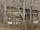 Exterior log cabin view amidst a wooded backdrop with a side door and window viewing access at 4401 E L G Rd, Efland, NC 27243