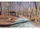 Scenic exterior shot showcasing a winding gravel driveway through a tranquil wooded landscape at 4401 E L G Rd, Efland, NC 27243