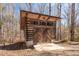Exterior log cabin garage provides parking and storage space, set amidst a wooded backdrop and a small window row at 4401 E L G Rd, Efland, NC 27243