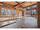 Rustic living space with exposed log beams, large windows, and a concrete floor offering natural light and access to the outdoors at 4401 E L G Rd, Efland, NC 27243