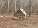 Rustic outbuilding made of stone and wood, nestled among trees in a serene outdoor setting at 4401 E L G Rd, Efland, NC 27243