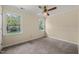 Neutral bedroom featuring two windows, a ceiling fan, and plush carpeting at 4508 Fox Rd, Raleigh, NC 27616