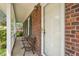 Close-up of the charming front porch with a vintage bench, brick facade, and a welcoming white door at 4508 Fox Rd, Raleigh, NC 27616