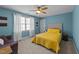 Bright bedroom featuring a yellow quilted bedspread, ceiling fan, and white curtains at 5317 Serather Ct, Garner, NC 27529