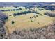 Aerial view of a sprawling property with fields and mature trees, showcasing the landscape at 5570 Normans Rd, Rougemont, NC 27572