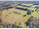 Aerial view showcasing lush green fields, a forest area, and a country road at 5570 Normans Rd, Rougemont, NC 27572