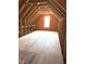 Unfinished attic space with wood beams, plywood subfloor, and natural light from a window at 6320 Slopeside Ct, Raleigh, NC 27610