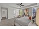 Bright bedroom with a ceiling fan, tray ceiling, cozy sitting area, and ensuite bathroom entrance at 706 Fireball Ct, Knightdale, NC 27545