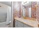 Bright bathroom featuring floral wallpaper, a vanity with a marble countertop, and shower/tub with white tiling at 7201 Jonathan Dr, Wendell, NC 27591