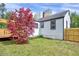 Spacious backyard with green lawn, shade tree, and charming white house at 829 Colleton Rd, Raleigh, NC 27610