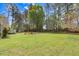 Vast backyard with a fire pit and chairs, green grass, mature trees, and a shed at 83 Wahoo Dr, Clayton, NC 27520