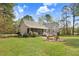 Spacious backyard with green grass, a fire pit with chairs, and gray siding on the house at 83 Wahoo Dr, Clayton, NC 27520