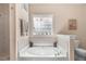 Soaking tub beneath a decorative window in a neutral colored bathroom at 83 Wahoo Dr, Clayton, NC 27520
