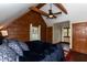 Cozy bedroom with wood-paneled walls, exposed beams, and a comfortable bed, creating a rustic retreat at 932 Gynnis Creek Dr, Moncure, NC 27559