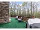 Open-air deck with green carpet, outdoor chairs, wooded view, and stone exterior wall at 932 Gynnis Creek Dr, Moncure, NC 27559