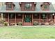 Inviting covered front porch with hanging plants, a green front door, and well-manicured landscaping at 932 Gynnis Creek Dr, Moncure, NC 27559