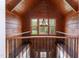 Open loft area featuring wood-paneled walls, a large window with scenic views, and decorative iron railing at 932 Gynnis Creek Dr, Moncure, NC 27559
