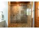 Close-up of glass shower with stone accents, pebble floor, and natural light streaming through the window at 932 Gynnis Creek Dr, Moncure, NC 27559