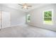Bright bedroom featuring carpet floors, a ceiling fan, and natural light from two windows at 105 Tuskeegee Dr, Smithfield, NC 27577