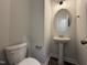 Stylish half bathroom featuring a modern pedestal sink, oval mirror, updated lighting, and white toilet at 105 Tuskeegee Dr, Smithfield, NC 27577