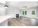 Open-concept living room with a fireplace, built-in shelves, and bright windows, flowing into a modern kitchen at 105 Tuskeegee Dr, Smithfield, NC 27577