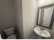 This bathroom features a white toilet, pedestal sink, gray framed mirror, and gray accent at 106 Roma Gora Ct, Princeton, NC 27569