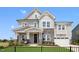 Two-story home with gray siding, stone accents, covered porch, and manicured landscaping at 108 E Fountainhead Ln, Garner, NC 27529