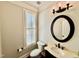 Half-bathroom features a vanity, round mirror, toilet, shutters on window with lots of natural light at 113 Woodland Ridge Ct, Cary, NC 27519
